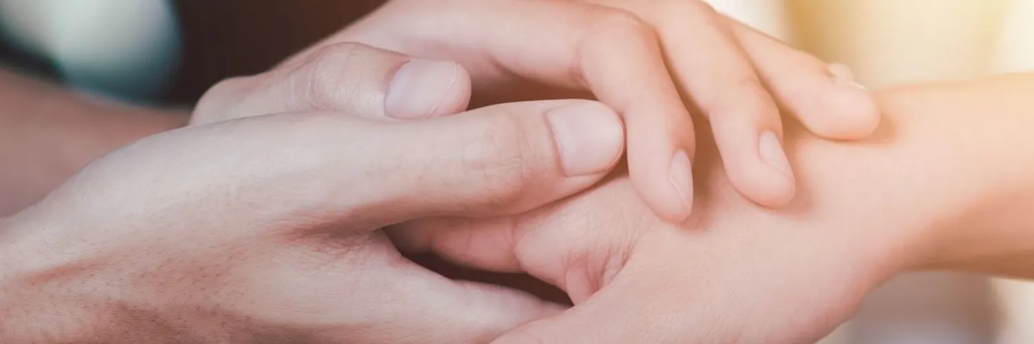 Dos manos sostienen la mano de otra persona en un gesto de acompañamiento cercano